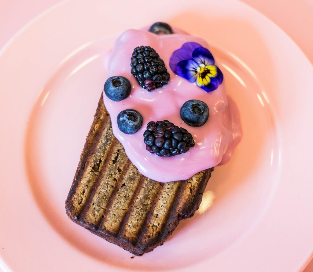 Banana bread with pink icing and berries