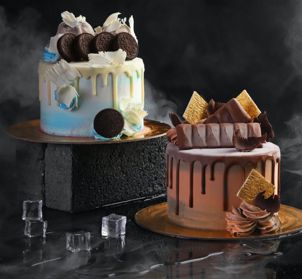 Two chocolate drip cakes with chocolate bars, oreo and white chocolate