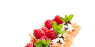 Brandy snap baskets with ice cream and berries isolated on white